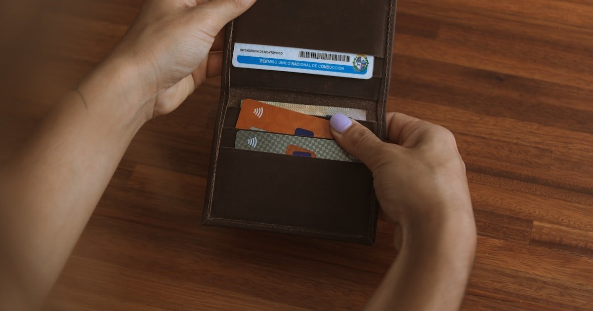 Hand holding a credit card near a payment terminal